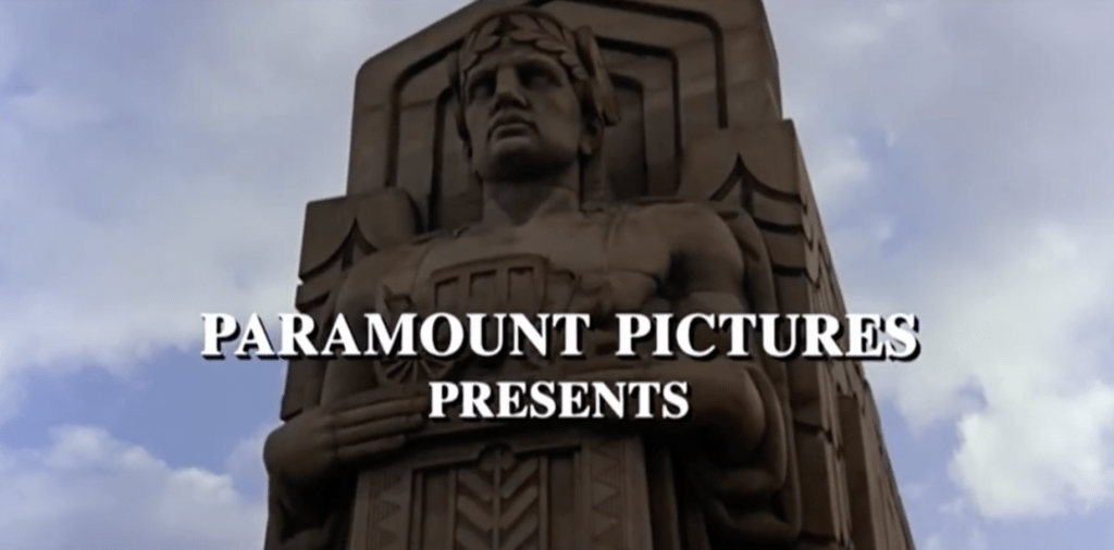 A shot from a film showing a large art deco stone statue with the text Paramount Pictures Presents
