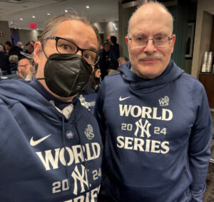 Two people wearing matching blue sweatshirts that say World Series 2024 on them with the Yankees logo